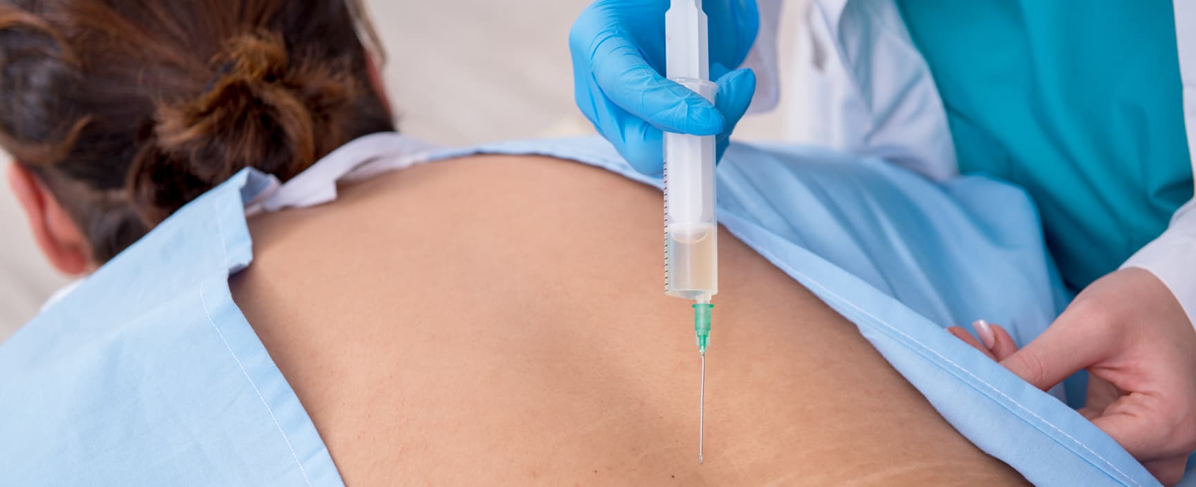 A woman receiving a cervical facet injection for pain management in her back