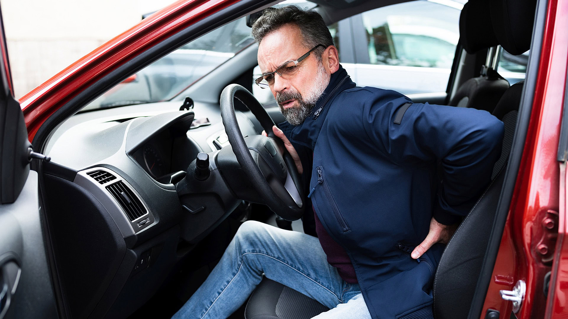 Man experiencing back pain while getting out of the car