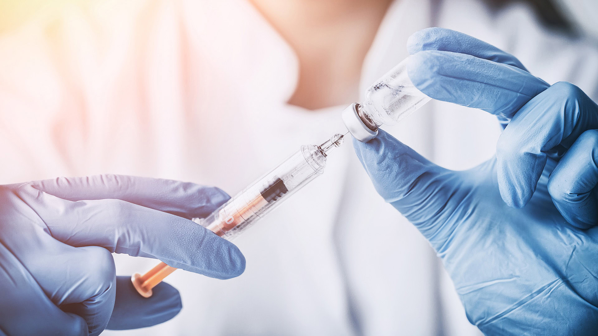 Doctor preparing vaccine in syringe