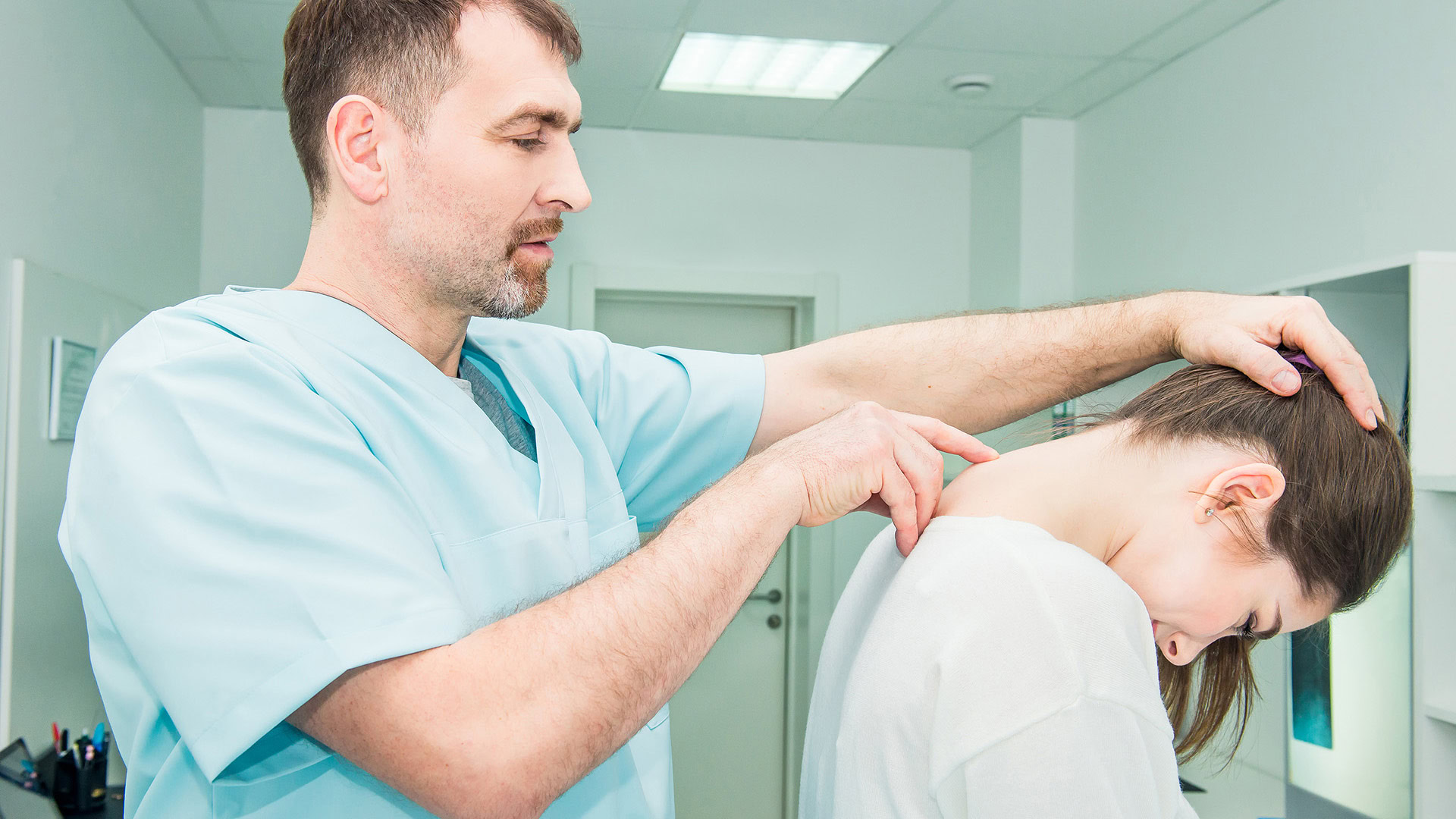 Neurologist examining patient's cervical spine in clinic