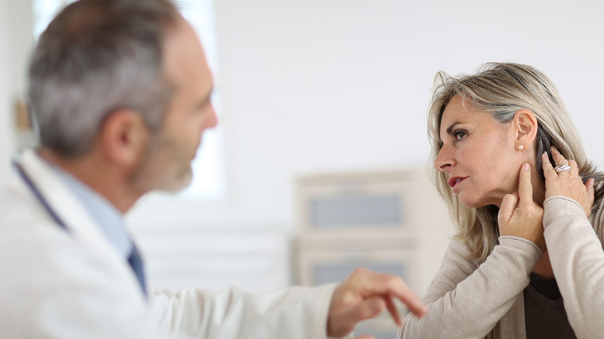 Elderly woman showing neck pain to doctor