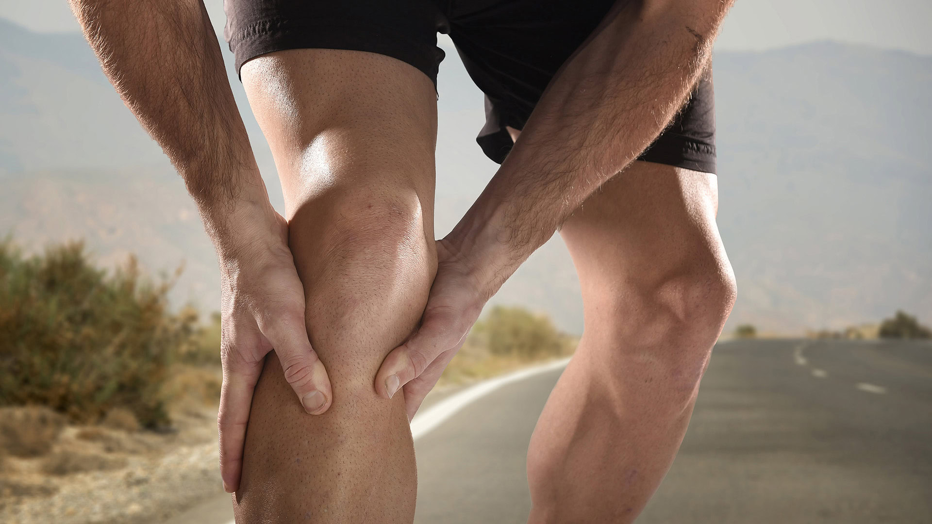 Athlete holding injured knee after running workout