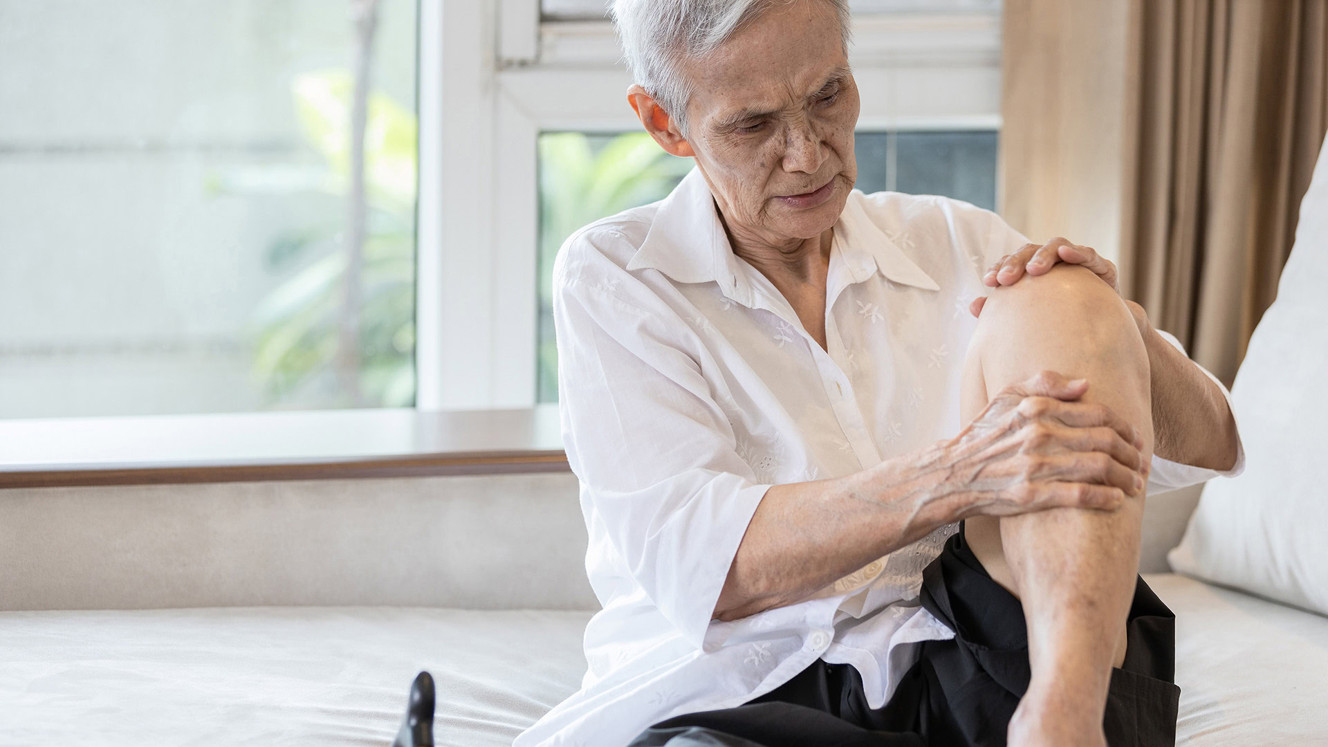 Elderly woman experiencing knee pain from arthritis