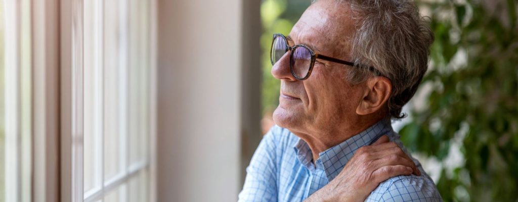 An Older Person Trying To Rub Away Upper Back Pain.