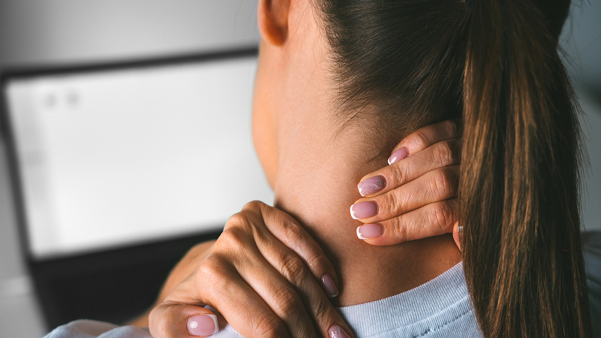 Woman massaging neck pain after computer work