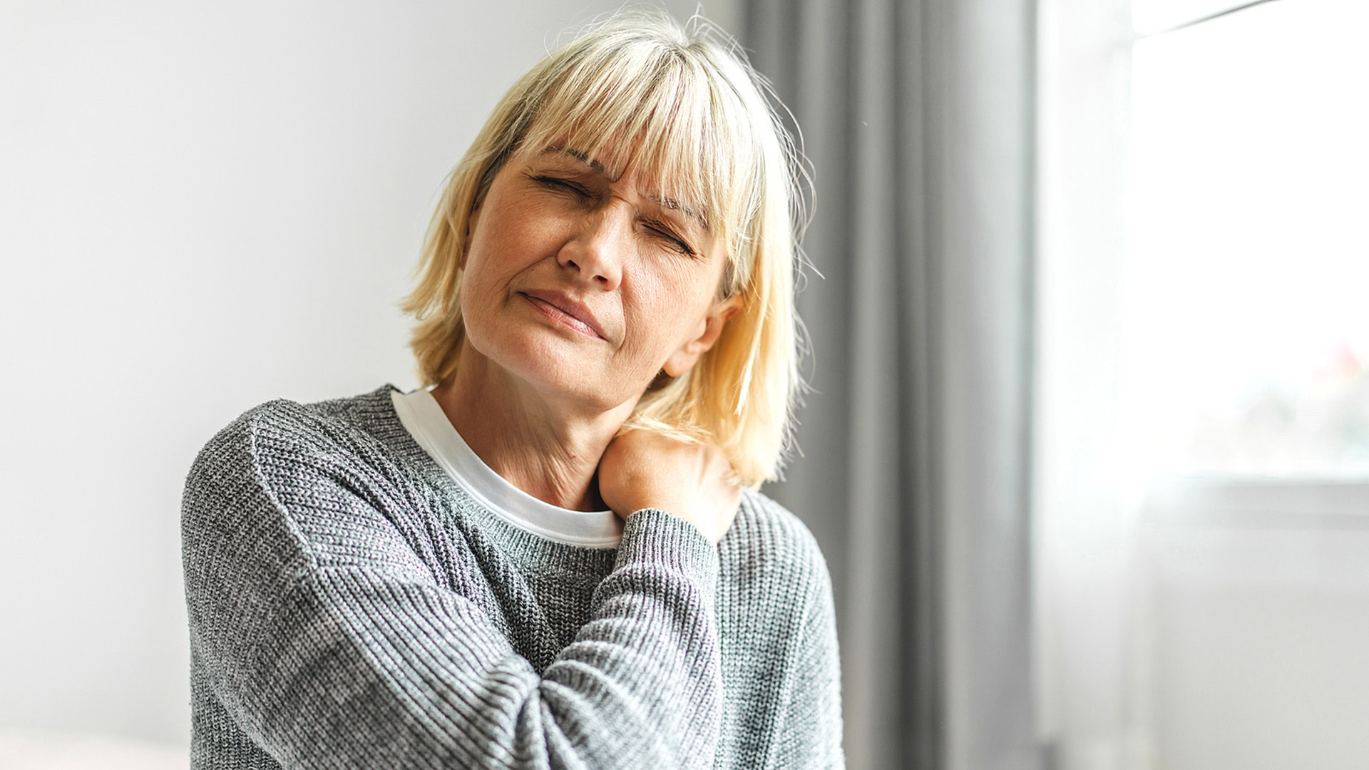 A women touching her shoulder suffering from neck pain at home